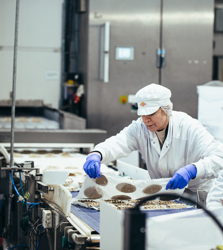 Bakery worker places pies on a conveyor belt