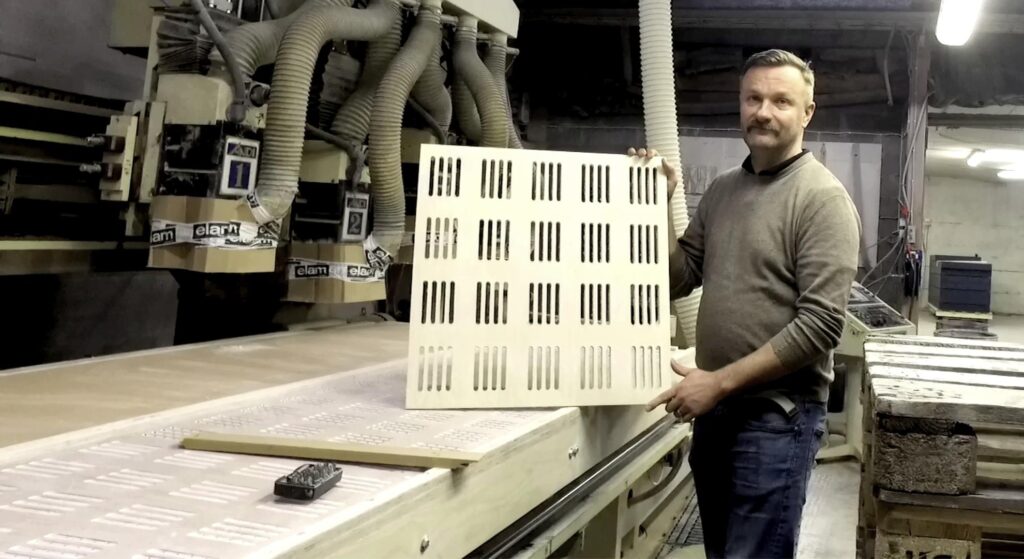 Man presents to wooden panel in the factory