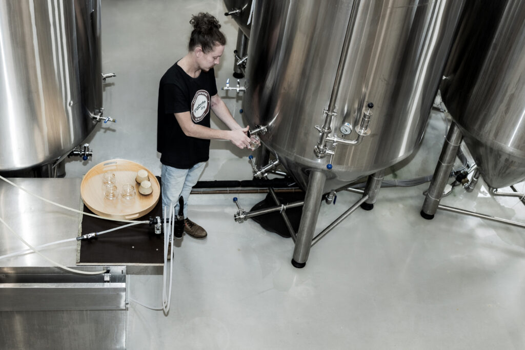 Andreas Wennström pouring fresh beer into glasses.