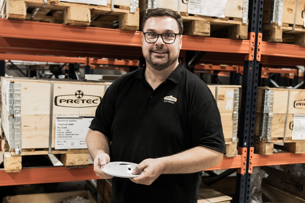 Mikael Lindberg stands at Pretec's warehouse and holds a metal fastener