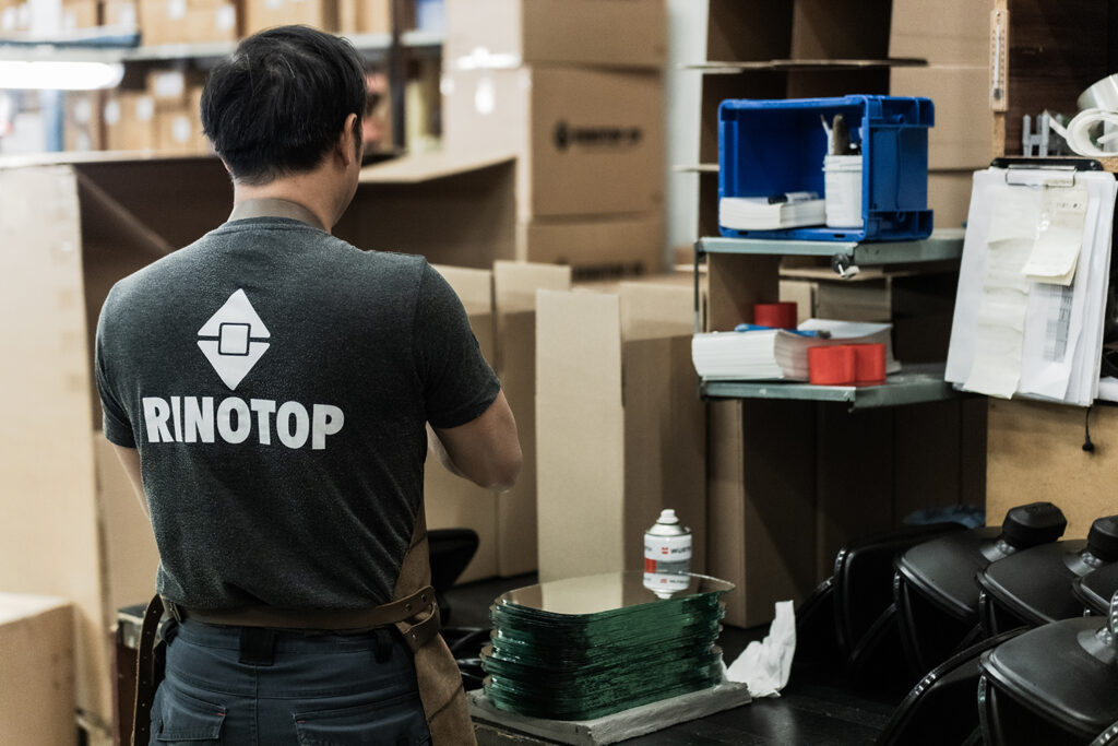 The worker stands with his back to the camera and assembles curved mirror products